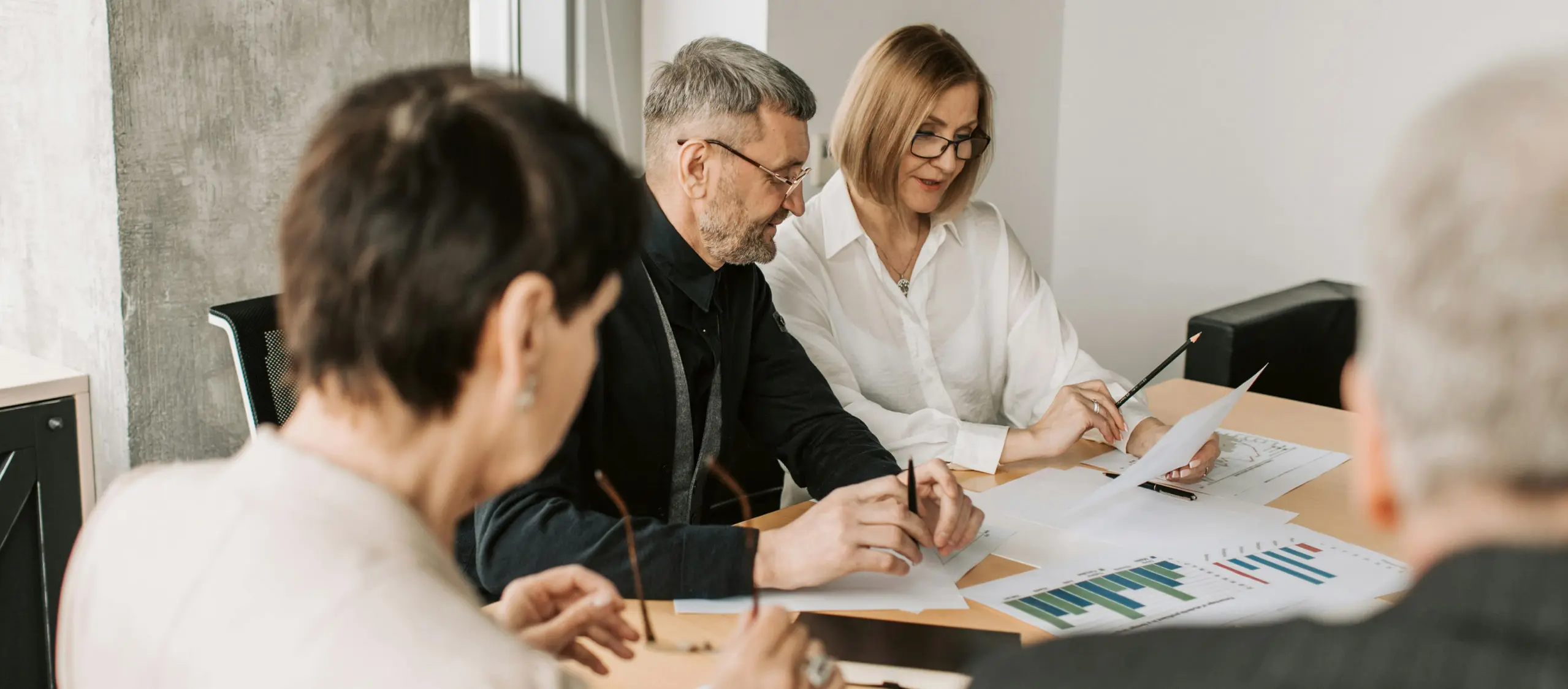 Mature couple and financial advisor reviewing loan charts at modern office table