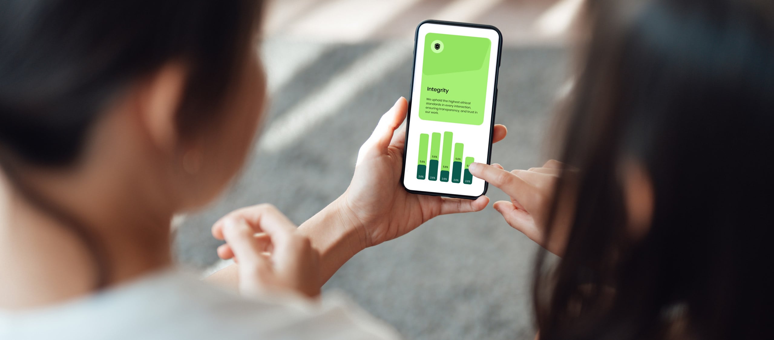 Person holding smartphone displaying 'Integrity' card and green finance bar chart