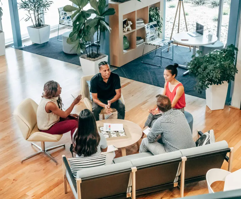 Five professionals collaborating around a coffee table in Freedom Capital Solutions&rsquo; modern Adelaide office lounge
