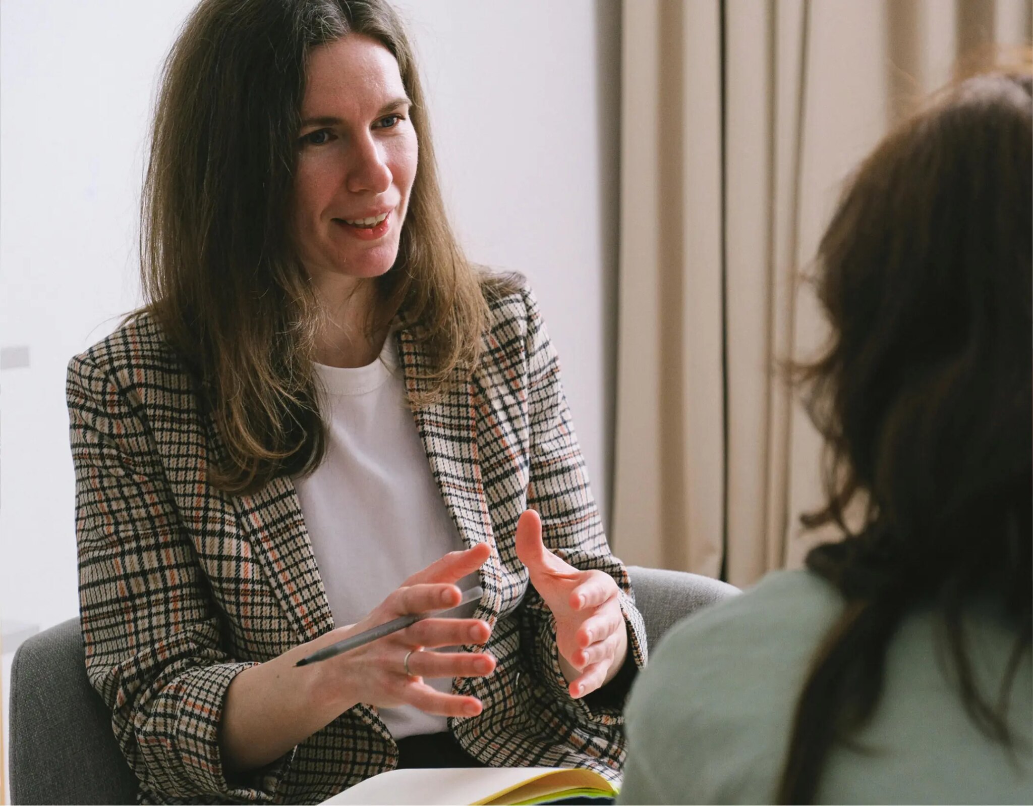 Female financial advisor in plaid blazer consulting client in modern office setting